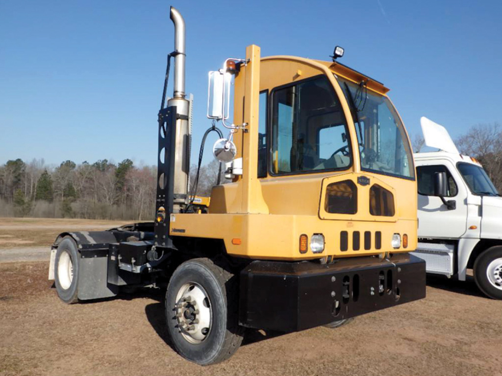 Autocar XSpotter heavy equipment chassis shown in yard with yellow cab, black frame, exhaust stack, and windowed cab.