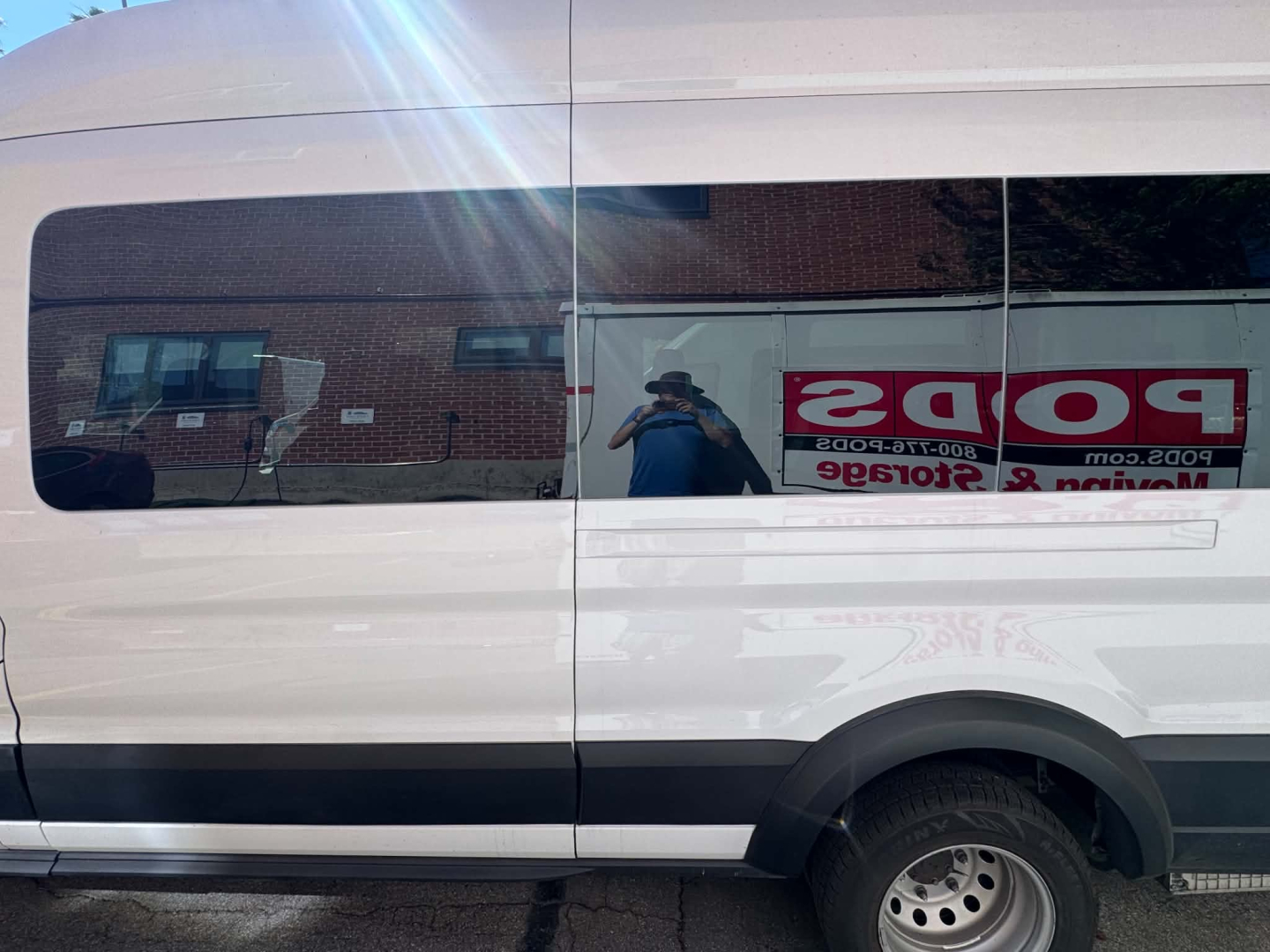 Van side view of a white 2022 Ford Transit 350 HD passenger van showing a long window and rear wheel area.
