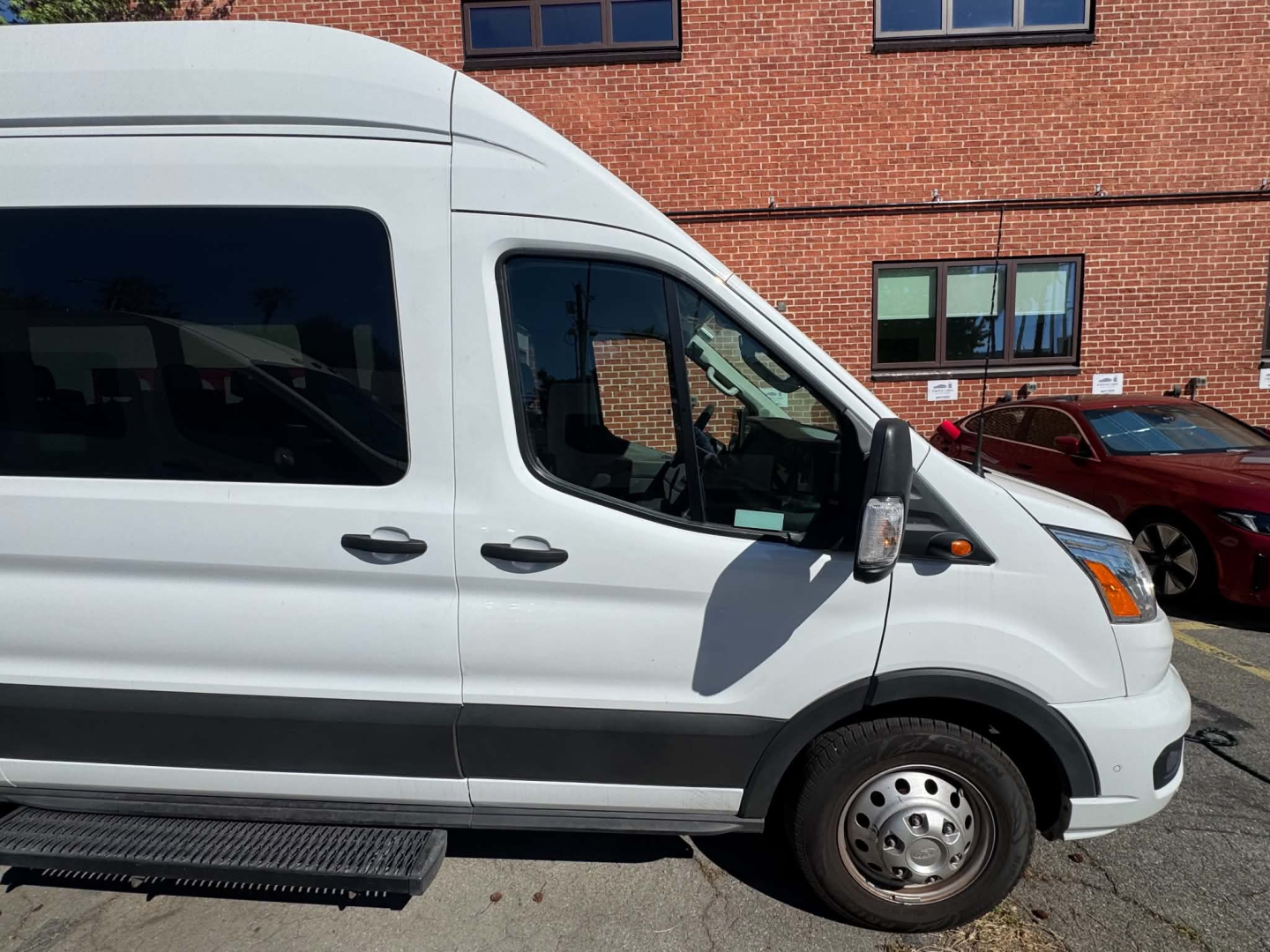 Ford Transit 350 HD van side view showing front door, wheel, and step in pristine exterior.