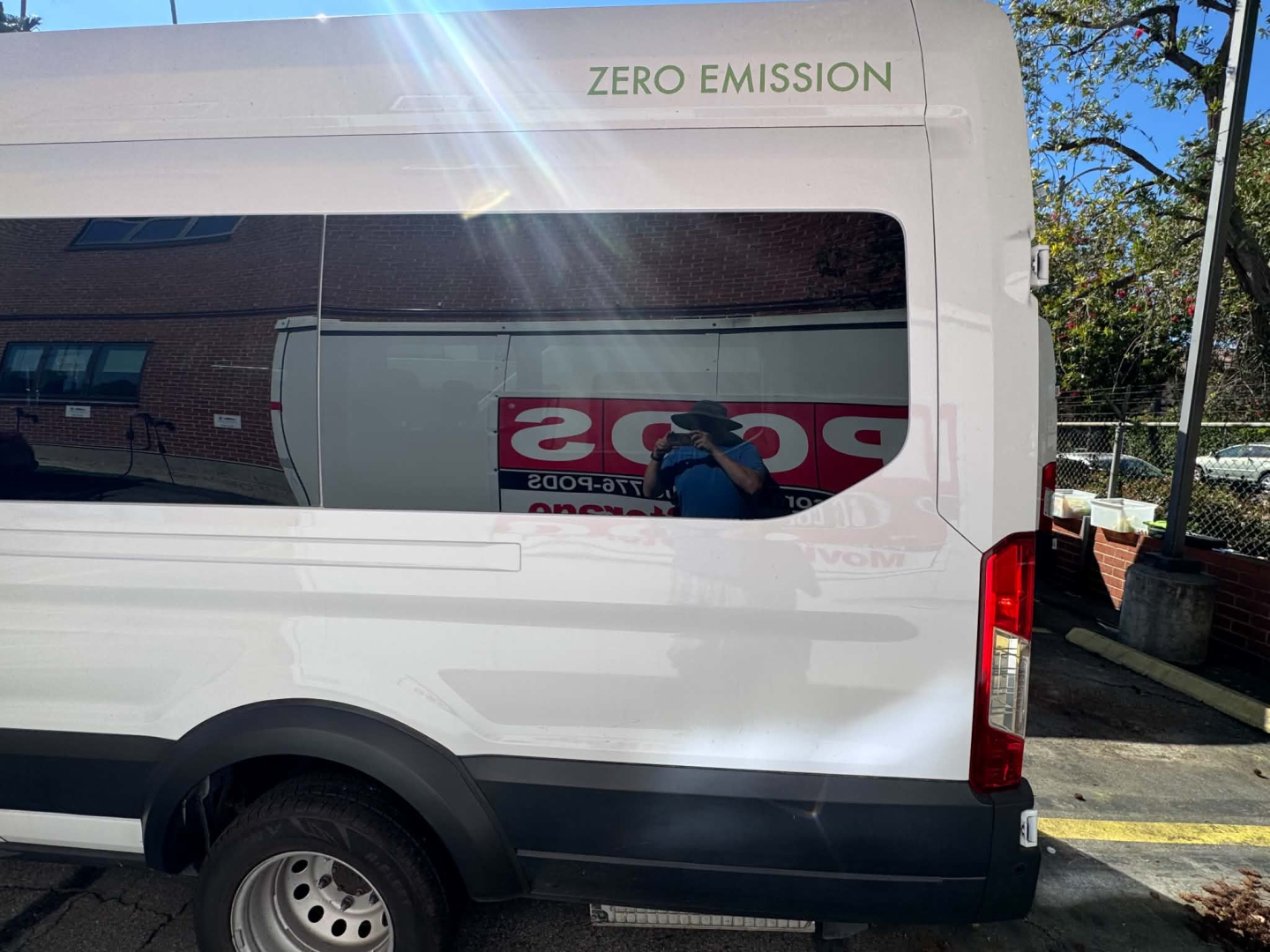Ford Transit 350HD van side rear showing zero emission decal and reflected text in window.