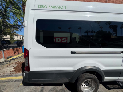 Ford Transit 350 HD van rear side with 'ZERO EMISSION' text on upper rear window and partial 'DSI' reflection in the glass.