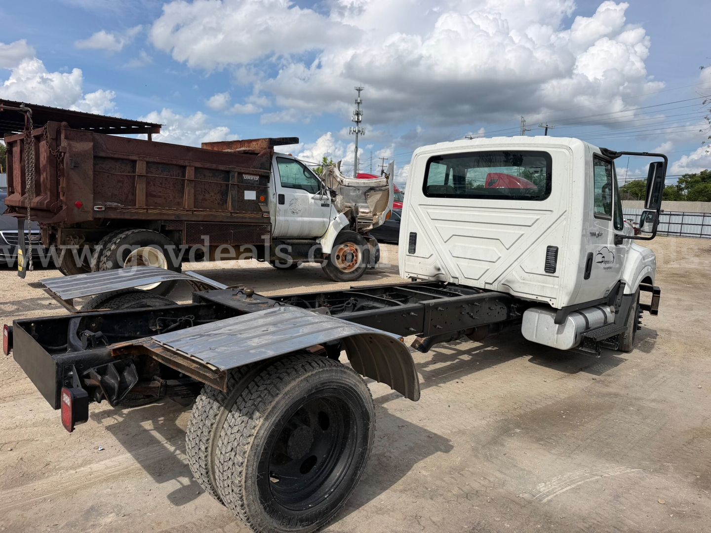 International TerraStar SFA 4x2 chassis with cab on a tilt-flatbed, single rear axle, white cab, black chassis rails, warehouse in background.
