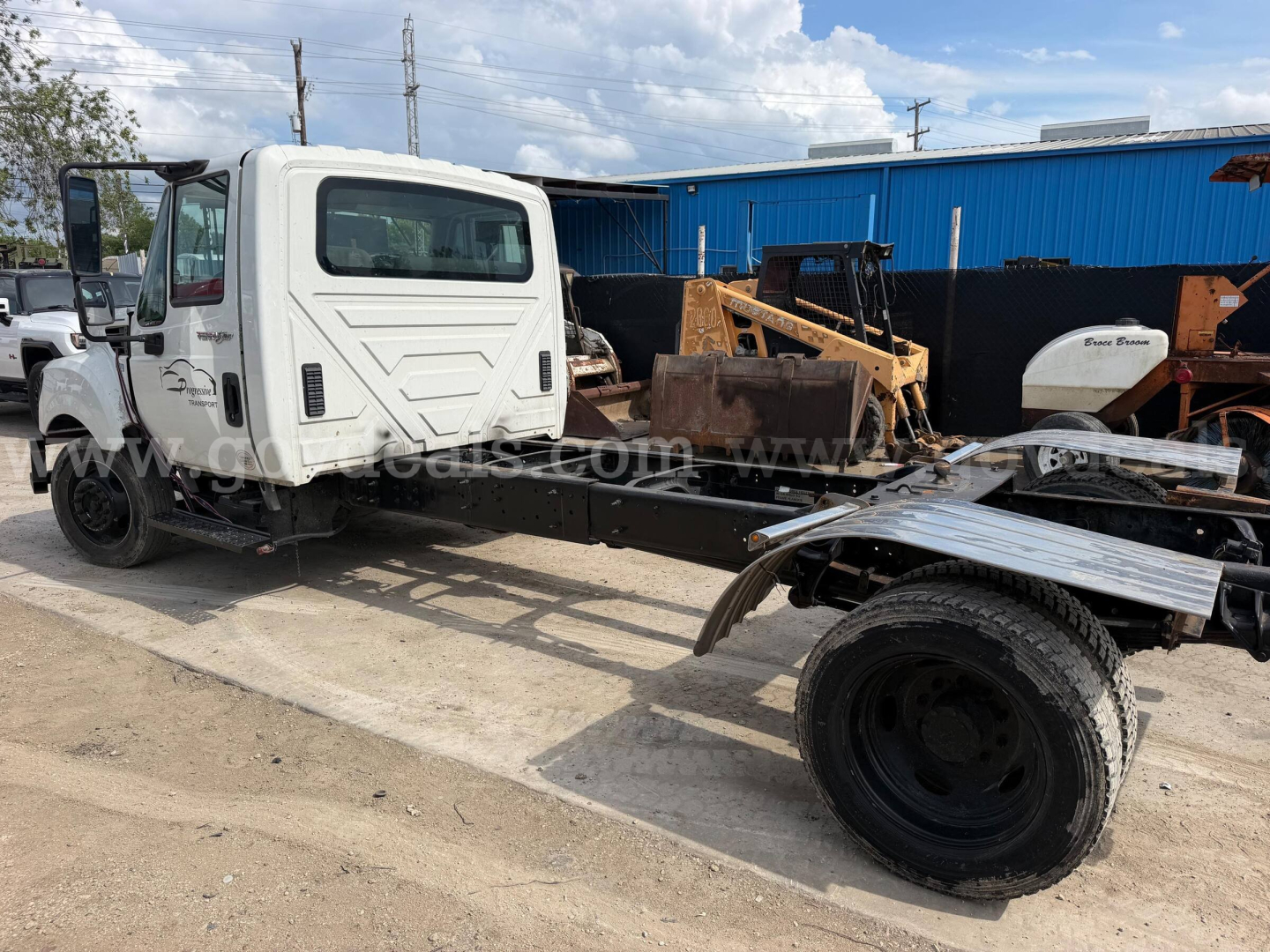 Truck cab of a 2014 International TerraStar SFA 4x2 chassis showing front cab and chassis with missing bed, white cab, black tires, and a blue building in background.