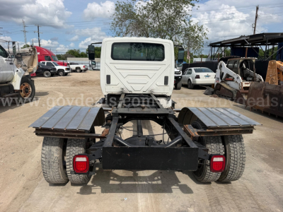 Truck chassis of a 2014 International TerraStar SFA 4x2 with cab rear view showing dual rear wheels and flatbed attachment points.