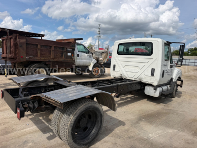 International TerraStar SFA 4x2 chassis with cab on a tilt-flatbed, single rear axle, white cab, black chassis rails, warehouse in background.