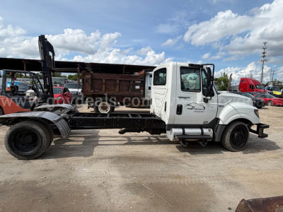 International TerraStar SFA 4x2 dump truck cutaway showing cab and chassis with flatbed body on trailer in a used-truck lot.