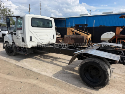 Truck cab of a 2014 International TerraStar SFA 4x2 chassis showing front cab and chassis with missing bed, white cab, black tires, and a blue building in background.