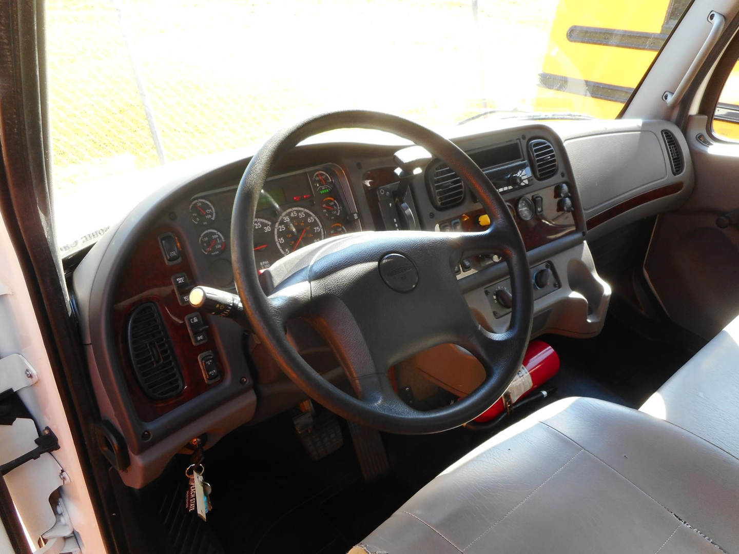 Freightliner M2 106 cab interior showing steering wheel, dashboard gauges, and controls.