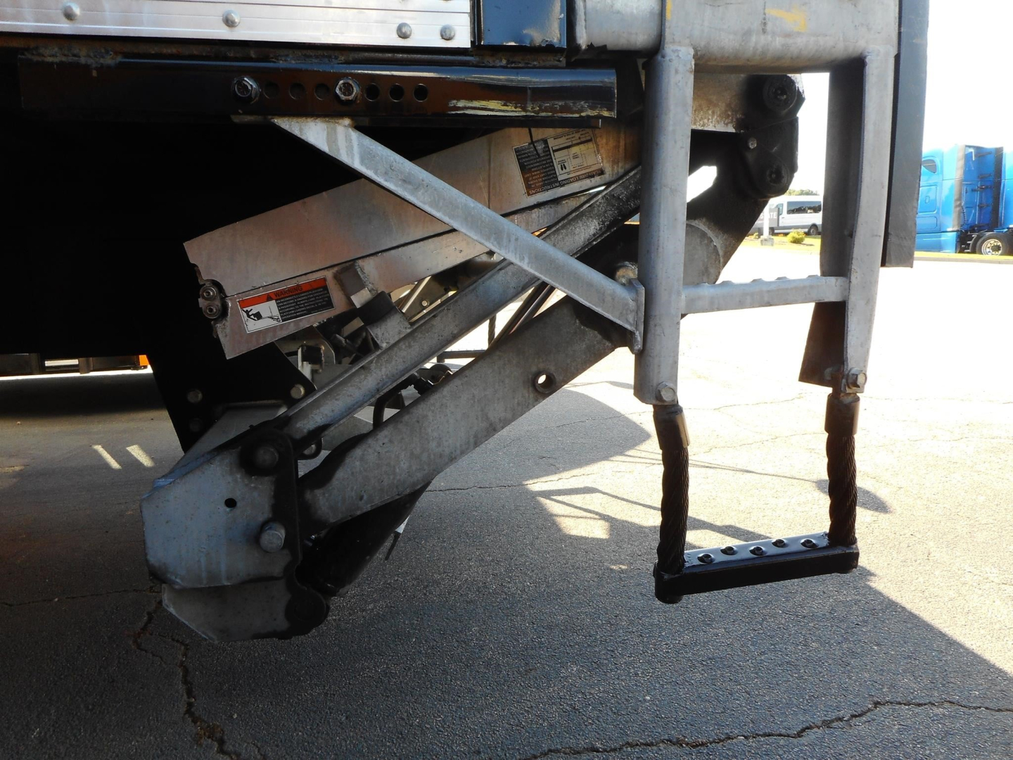 Rear view of a Freightliner M2 106 truck showing the drop-down liftgate hardware and steps with metal support braces.