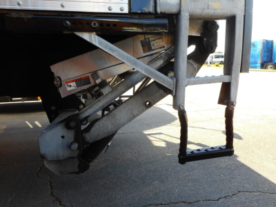Rear view of a Freightliner M2 106 truck showing the drop-down liftgate hardware and steps with metal support braces.
