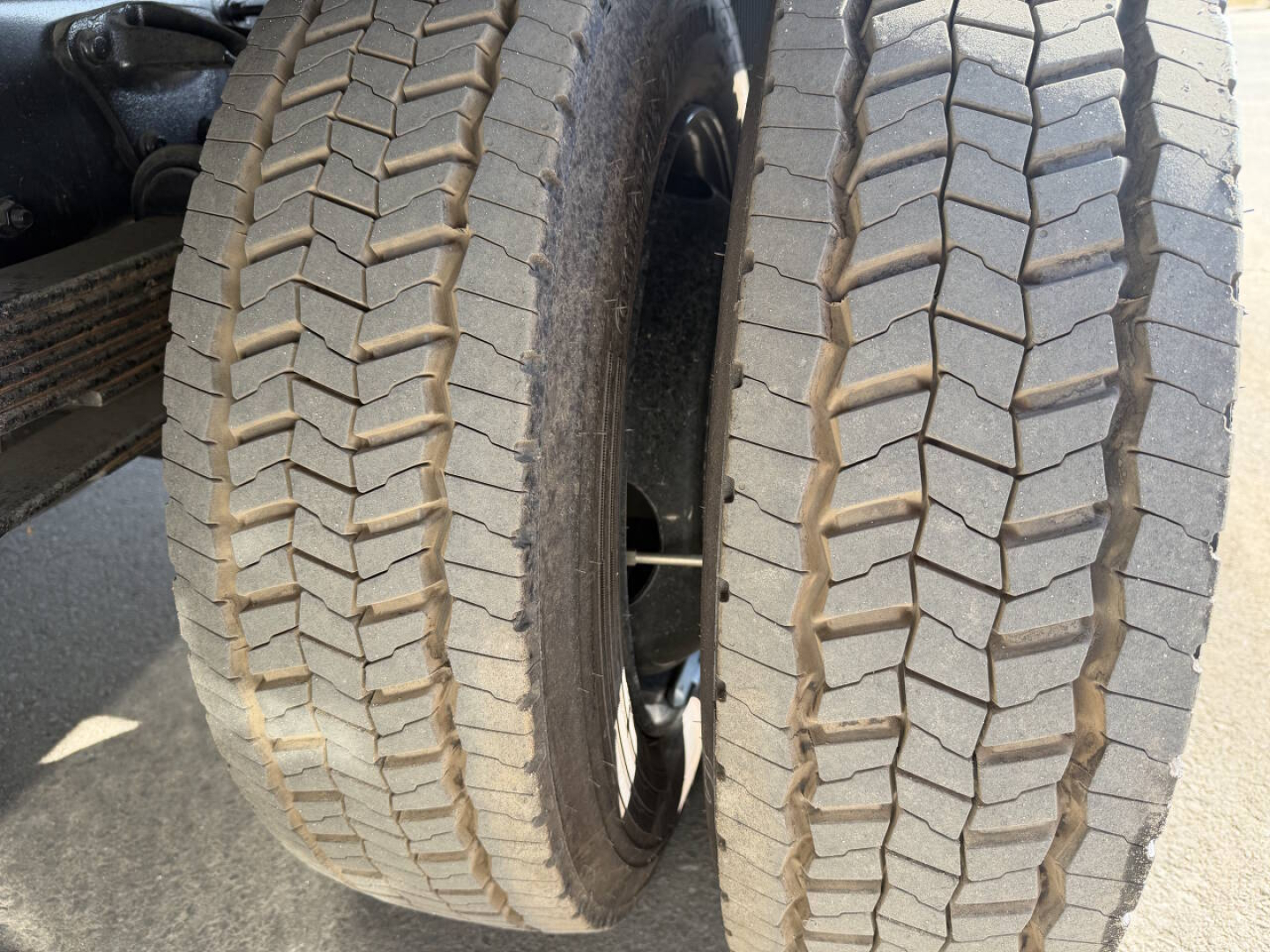 Dual rear truck tires with prominent tread pattern, viewed from side; part of chassis and wheel wells visible.
