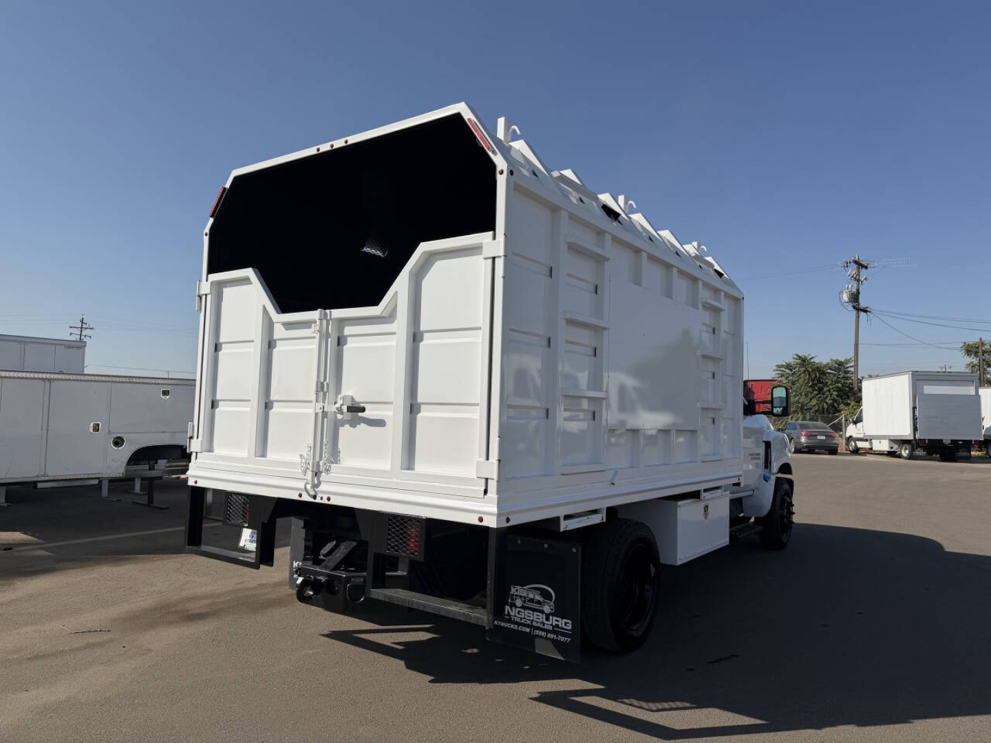 White Chevrolet 6500 HD dump truck with dump body, rear view showing tailgate, undercarriage, and black wheels.