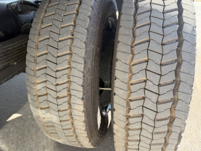 Dual rear truck tires with prominent tread pattern, viewed from side; part of chassis and wheel wells visible.