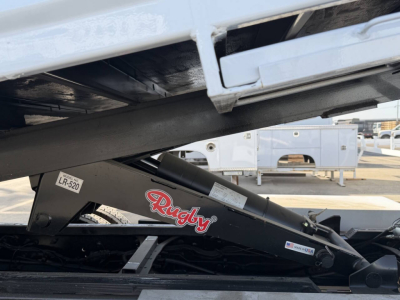 Truck chassis showing a Rugly hydraulic lift arm with label and white cab area above.