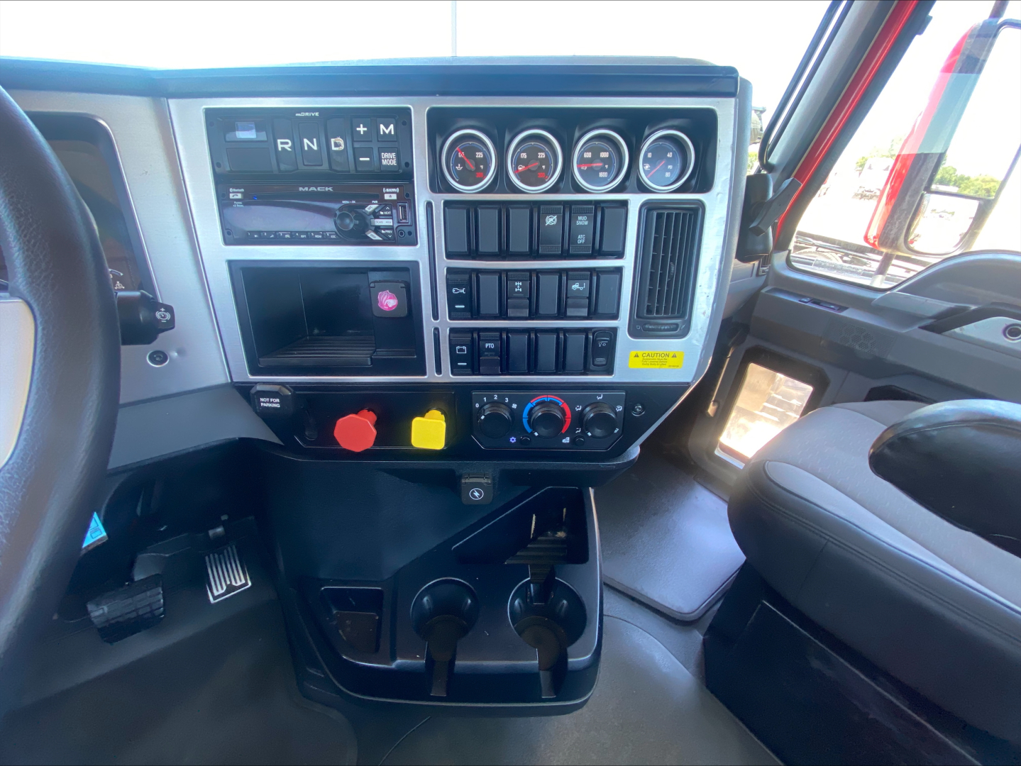 Truck cab dashboard with gear selector, multiple gauges, switches, and controls; visible text includes R N D P and +/- on gear panel, various gauges, climate and accessory controls.