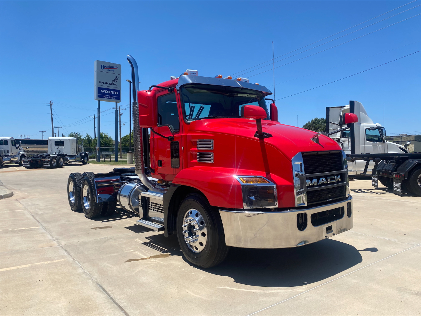 Mack AN64T conventional daycab truck in red with chrome front bumper and dual rear axles, parked in lot.