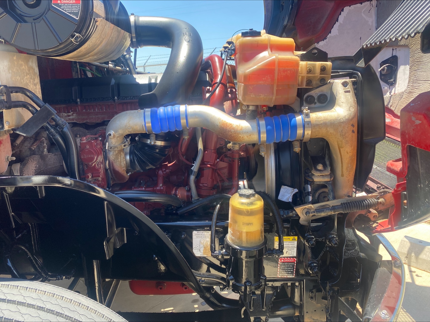 Engine bay of a 2021 Mack AN64T conventional daycab showing hoses, reservoirs, and components