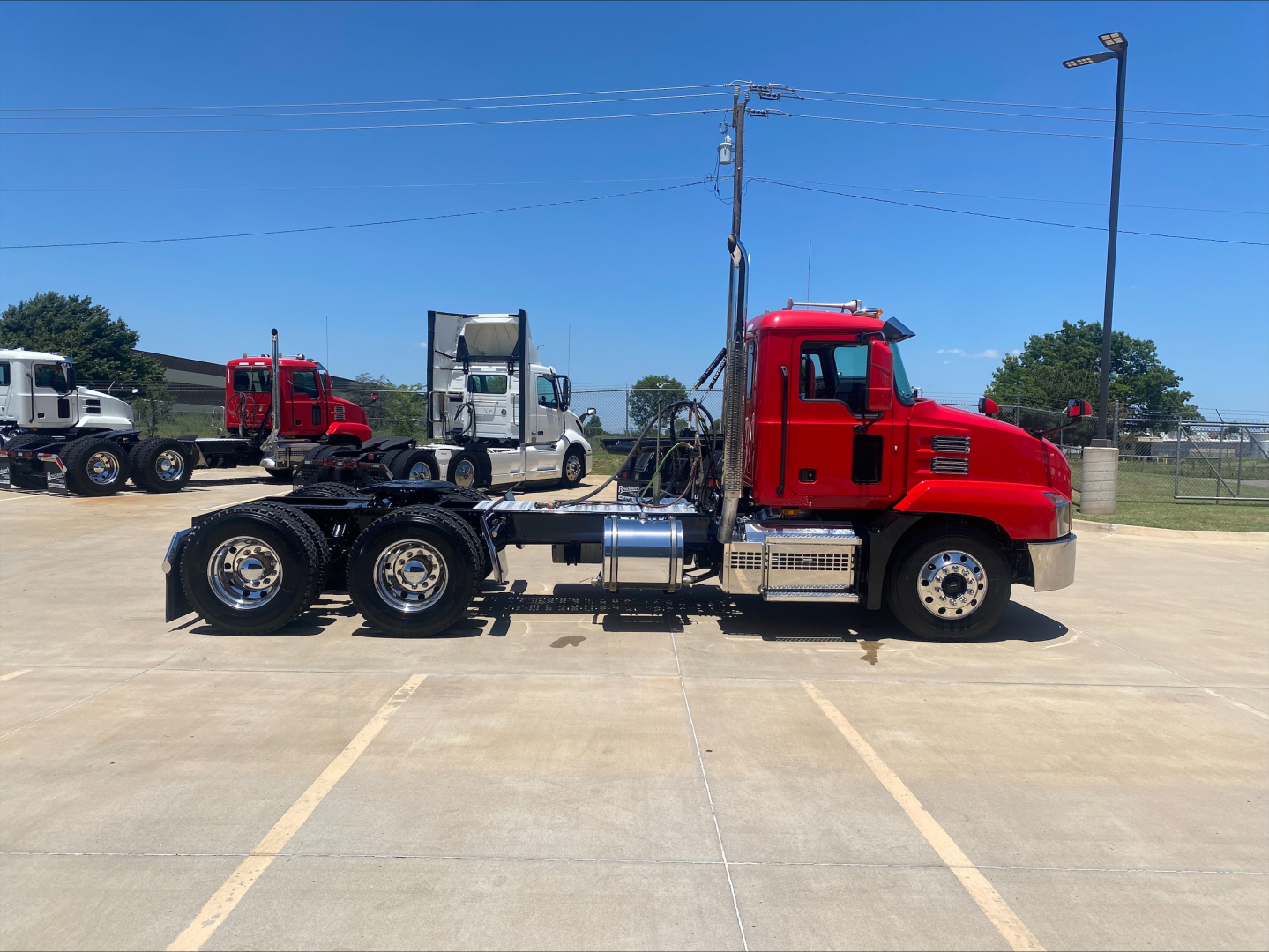 Mack AN64T conventional daycab truck side view showing red cab and chassis with dual rear axles, fuel tanks, and exhaust stack.