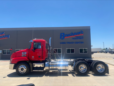 2021 Mack AN64T daycab truck viewed from side showing chassis and wheels in front of truck center building.