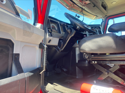 Cab interior of a 2021 Mack AN64T daycab showing steering wheel, dashboard gauges, driver's seat, pedals, and open passenger area.
