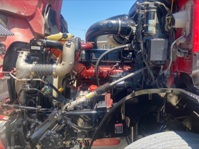 Engine bay of a Mack AN64T daycab showing engine components, hoses, filters, and surrounding framework.