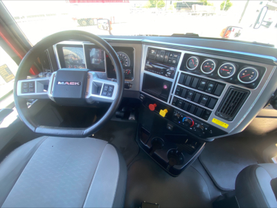 Mack AN64T truck interior showing steering wheel and instrument cluster with multiple gauges and control switches.