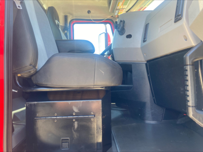 Cab interior of a Mack AN64T daycab showing driver's seat and dashboard with storage box under seat.
