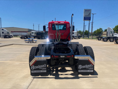 Rear view of a red 2021 Mack AN64T daycab tractor showing rear mud flaps with 'Bruckners USED TRUCKS OKLAHOMA CITY' text, and chassis details.