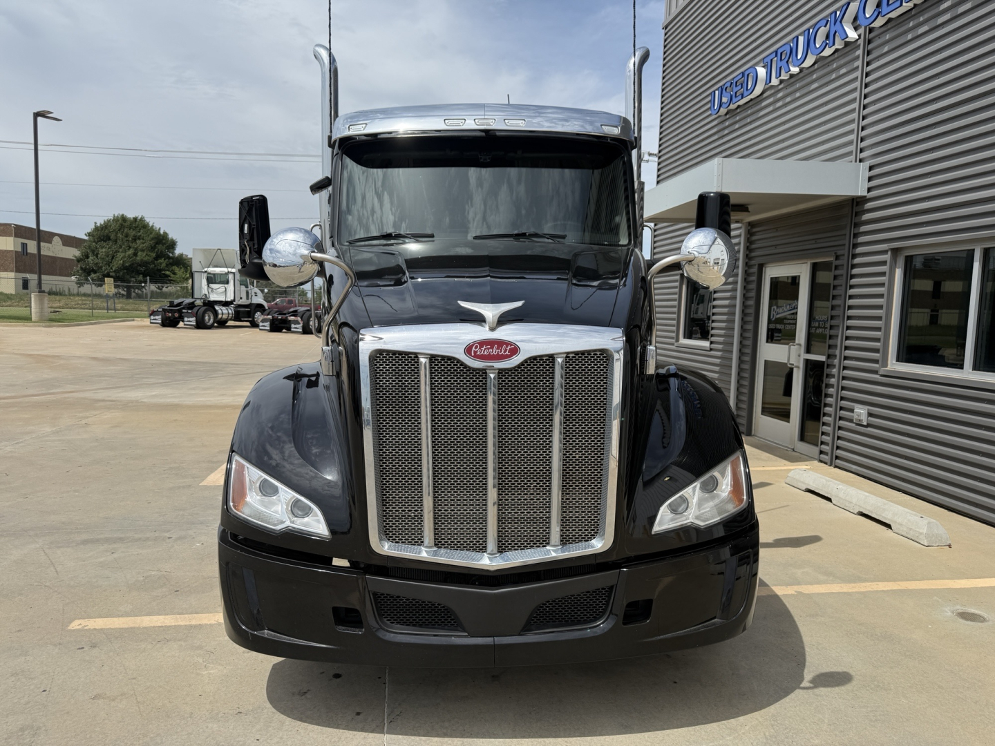 Peterbilt 579 truck front view showing chrome grille, headlights, side mirrors, and badge in black paint.