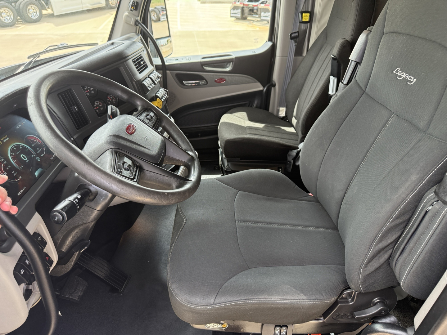 Peterbilt 579 interior showing driver seat and dashboard with steering wheel and Legacy seating tag on seat.
