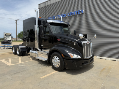 Peterbilt 579 conventional sleeper truck in black, front-right view, chrome exhausts, fuel tanks, and dual rear axles visible.