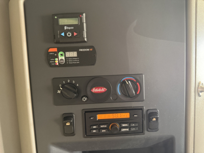 Peterbilt 579 dash area showing Dash-mounted control cluster including Freedom HF unit, Beckett/Espar heater controller, and radio; various knobs and vents visible.