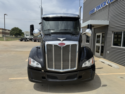 Peterbilt 579 truck front view showing chrome grille, headlights, side mirrors, and badge in black paint.