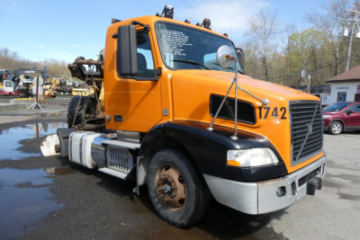 Volvo VNM42T conventional daycab truck in orange with black grille, showing front-right view and large number 1742 on the hood