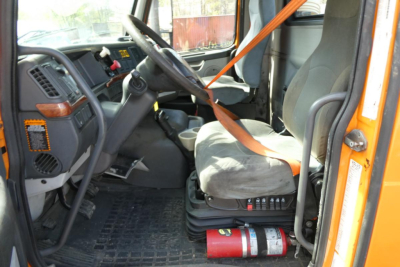 Cab interior of 2012 Volvo VNM42T conventional daycab showing driver seat, steering wheel, dashboard, and orange seat belt.