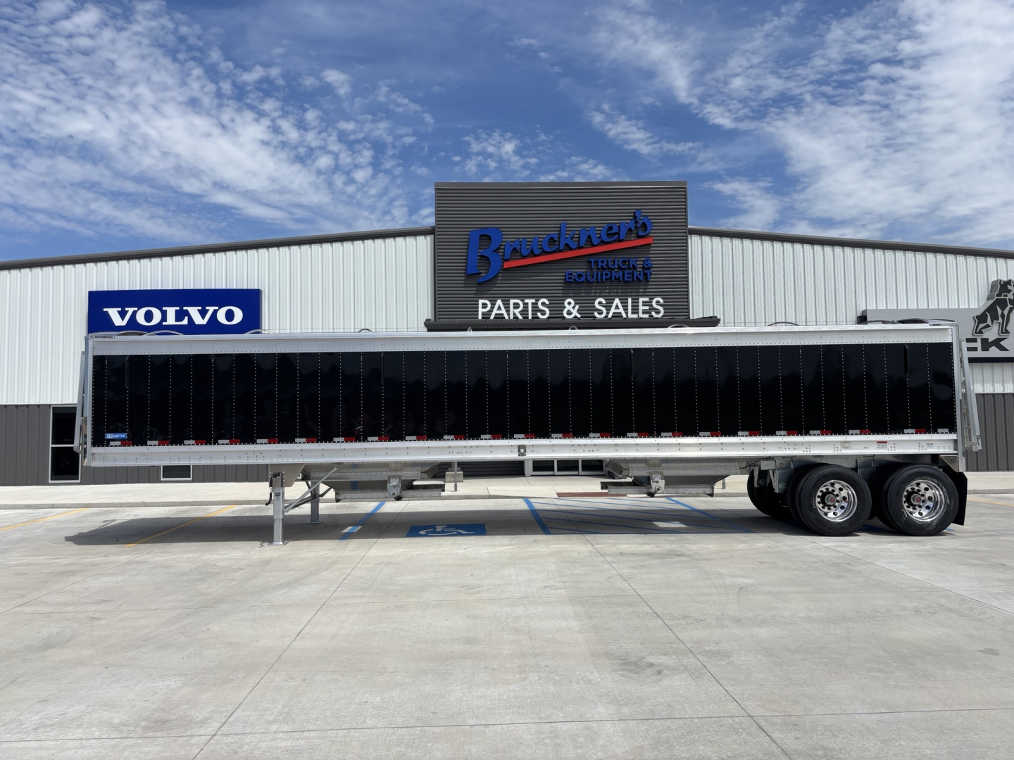 New 2027 Stoughton 42' aluminum grain hopper trailer with 74" sides, parked in lot; side view showing black side panels and tandem axles.