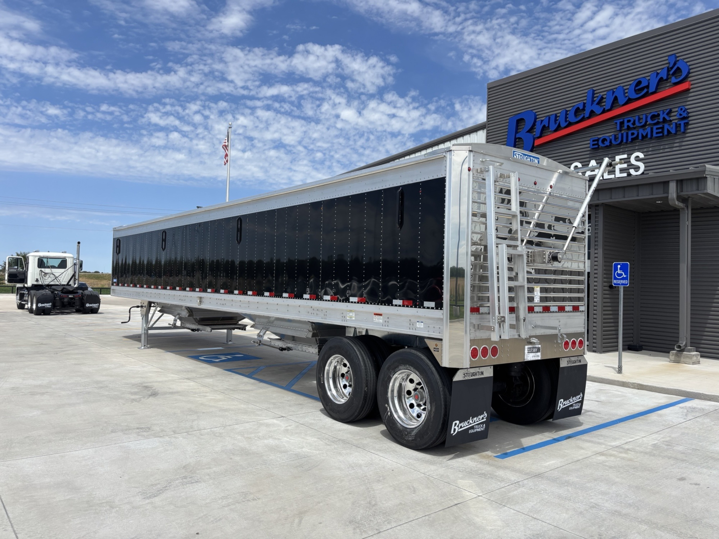 Trailer showing 42' aluminum grain hopper with 74-inch side walls, dual rear axles, black side panels, aluminum ladder and rear frame.