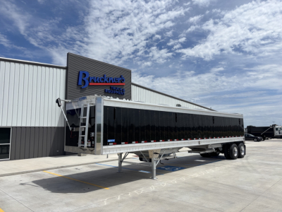 Stoughton 42' aluminum grain hopper trailer with 74" sides, black side panels, dual tandem axles, parked outside a dealership.