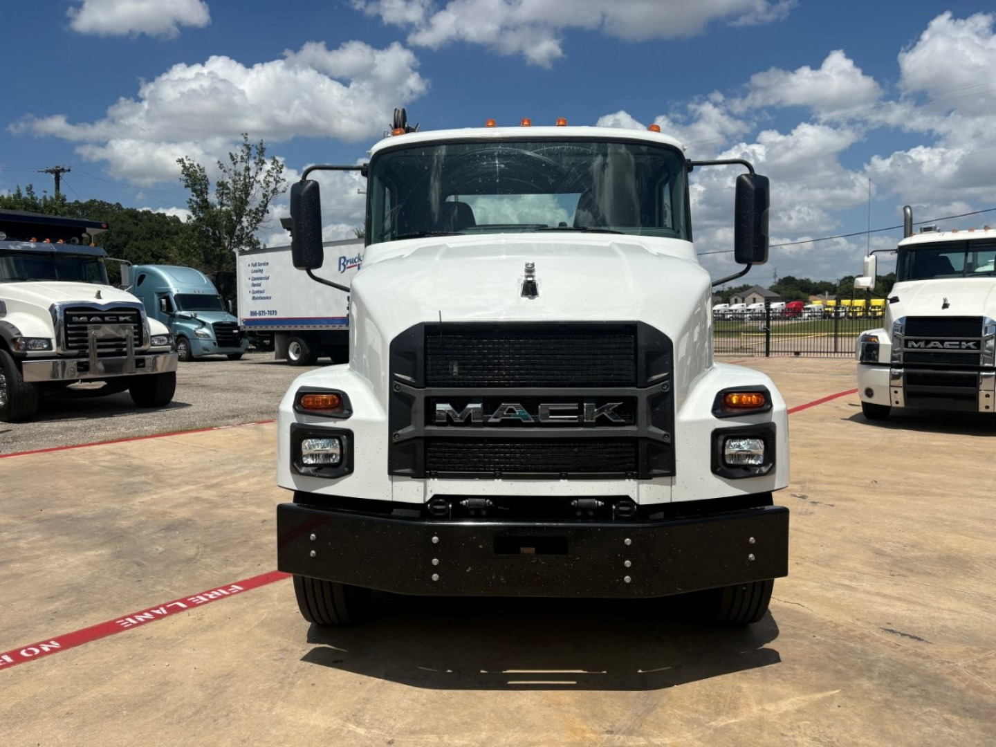 Mack MD6 front view showing grille with MACk badge, white cab, black front bumper, orange marker lights on roof, headlights, side mirrors.