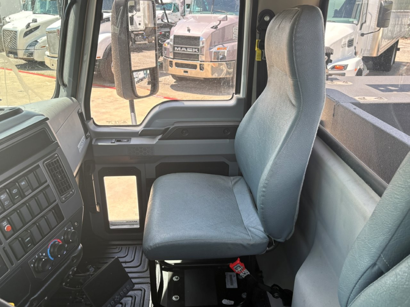 Interior cab view of a 2024 Mack MD6 truck showing the driver seat, steering wheel area, and dashboard with controls.