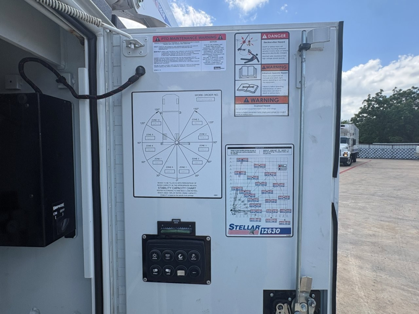 Mack MD6 service door with warning labels, control panel, and wheel/listing diagrams. Visible stickers include warning icons and a Stellarr 12630 label near the door frame.