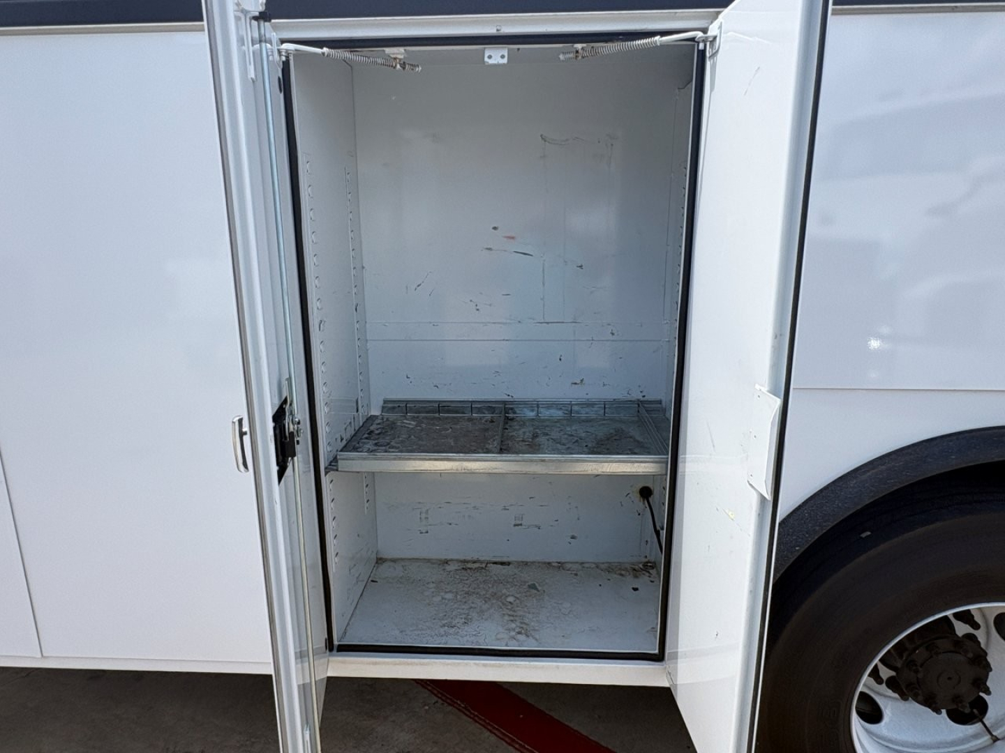 Mack MD6 service truck with open rear storage compartment showing empty shelf and interior walls.