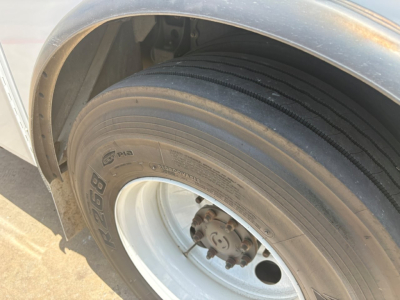 Truck wheel and fender view showing front tire and hub with rim and brake components