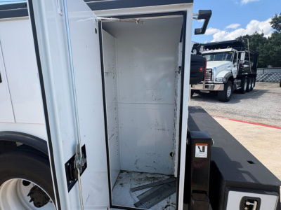 Truck service bed interior showing empty metal cargo area with white walls and a textured floor on a white and black Mack MD6 chassis.