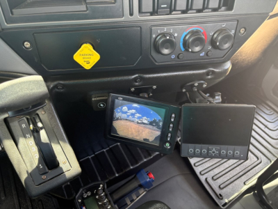 Dashboard and control panel of a Mack MD6 truck cab with gear selector, climate controls, and a dash-mounted camera monitor showing rear view.