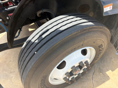 Mack MD6 front wheel showing dual rear tires and lug nuts; partial suspension and wheel well visible.