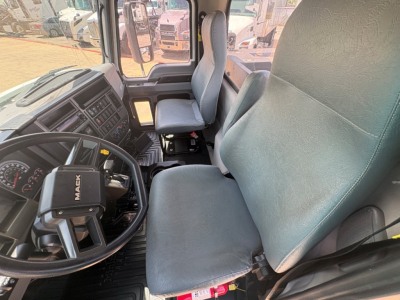 Mack MD6 interior showing driver seat, steering wheel, and dashboard with gauges; cab view from passenger seat.