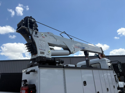 Mack MD6 service/utility truck with a mounted boom crane as seen in cargo bed; side panels, controls, and hydraulic components visible.