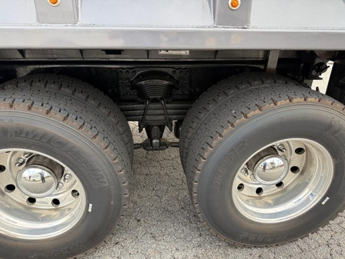 Dual rear wheels and suspension view of Western Star 47X dump truck showing tandem axle and leaf springs under chassis.