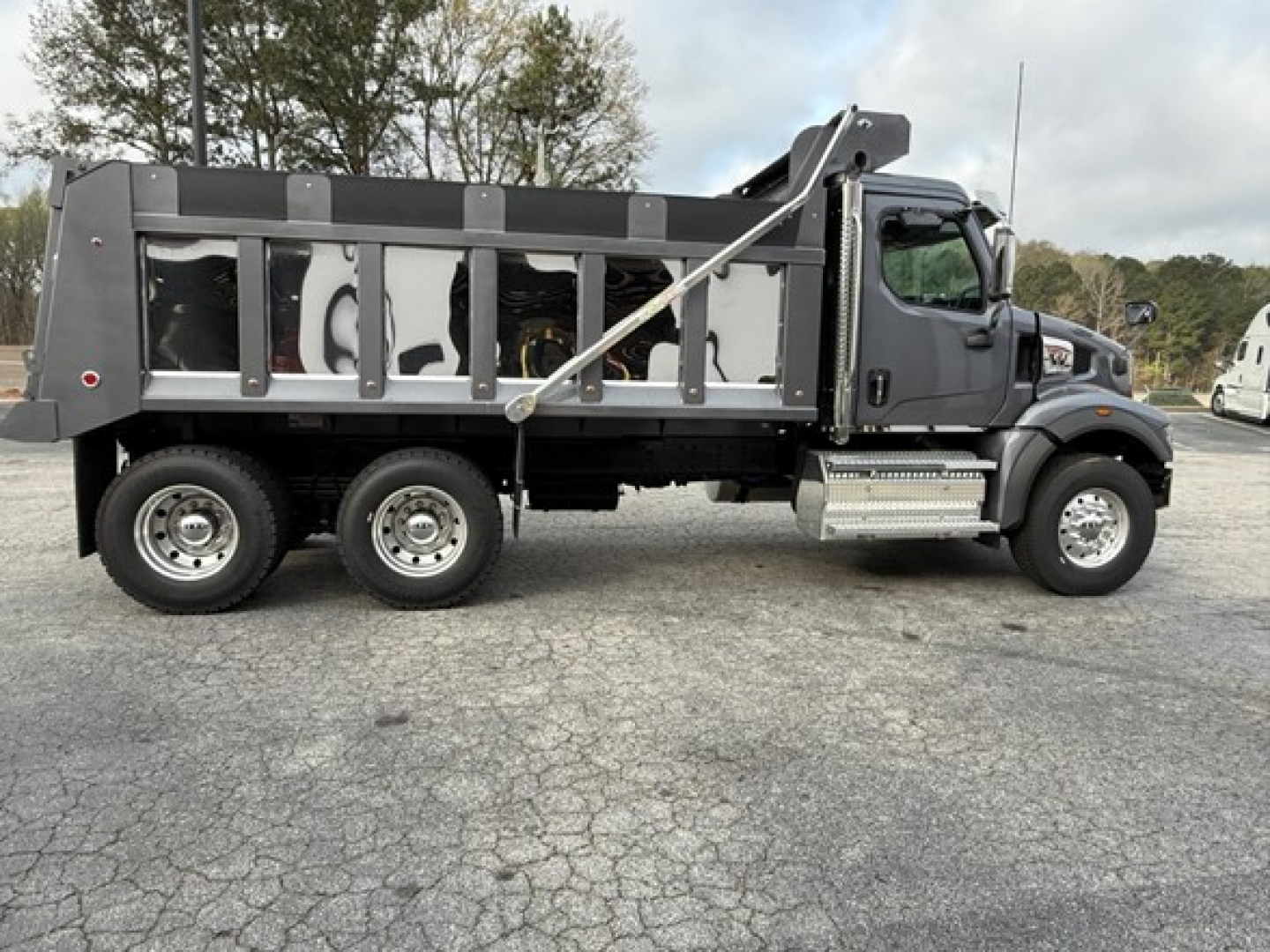 Western Star 47X dump truck side profile showing dump bed, cab, dual rear wheels, and hydraulic hoist with frame-mounted steps.